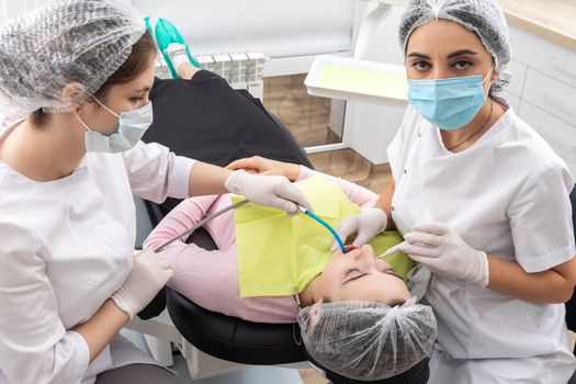 Professional dentist surgeon and assistant performing dental operation in a clinic with modern equipment