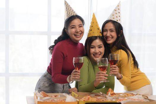 Group of happy young Asian people with friends celebrating clinking glasses during dinner party.