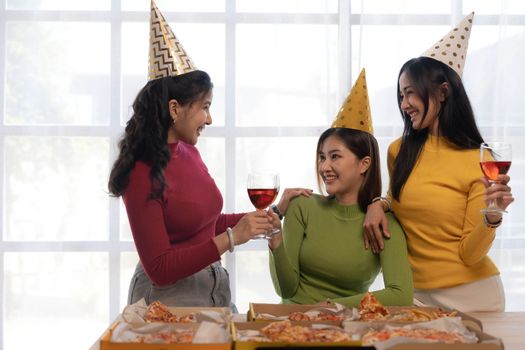 Group of happy young Asian people with friends celebrating clinking glasses during dinner party.