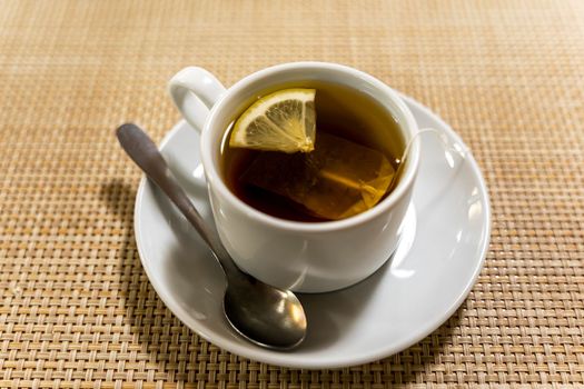 an elegant white cup of tea with a slice of lemon on the table. breakfast, morning tea, snack.