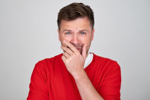 upset crying man in red sweater gesturing with his hands. Do not be shy to cry concept. Studio shot