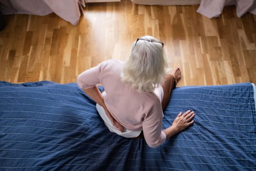 Senior woman suffering of backache, touching back with hand, muscular pain. Top view