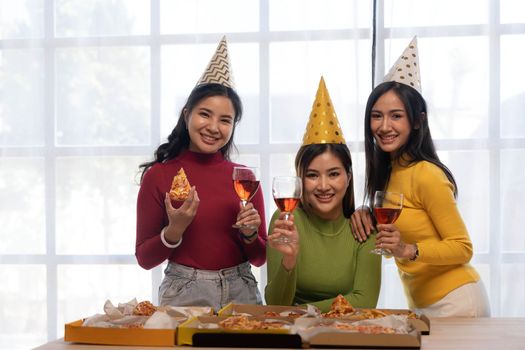 Group of happy young Asian people with friends celebrating clinking glasses during dinner party.