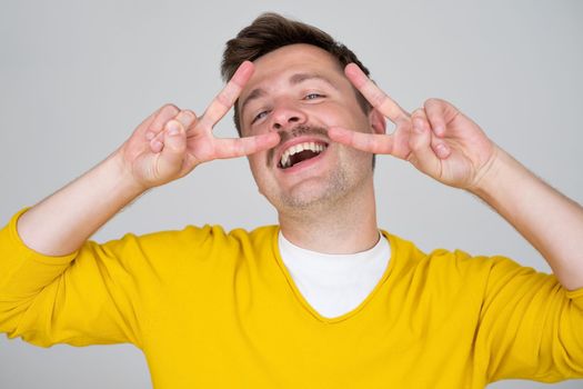 Young handsome man showing fingers doing victory sign. Number two. 