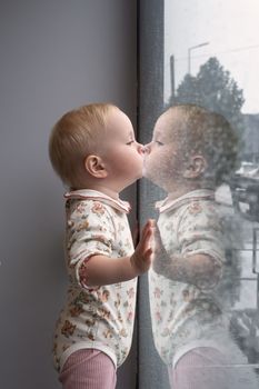 little caucasian baby girl watching the rain through the window. 