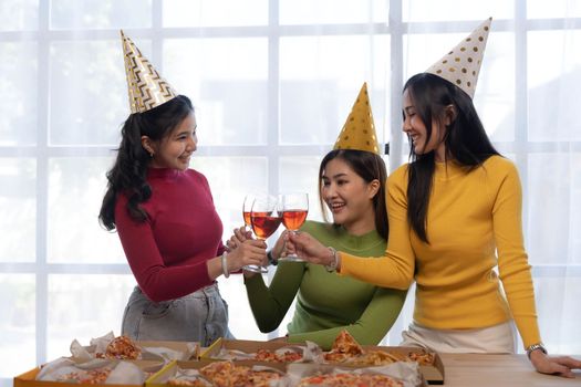 Group of happy young Asian people with friends celebrating clinking glasses during dinner party.