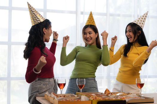 Group of happy young Asian people with friends celebrating clinking glasses during dinner party.