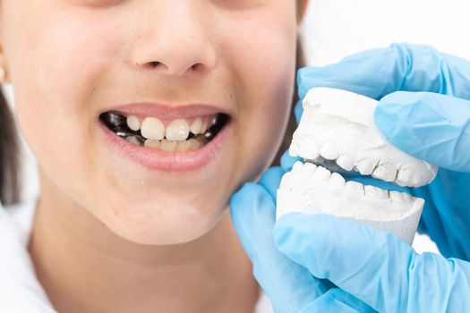 Portrait of little cute girl shows her orthodontic appliance on a white background.