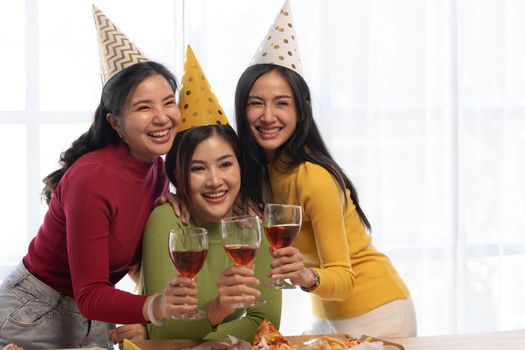 Group of happy young Asian people with friends celebrating clinking glasses during dinner party.