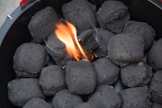 a man lights a fire with a lighter special charcoals for a barbecue a barbecue house on the terrace prepares a place for a barbecue. High quality photo