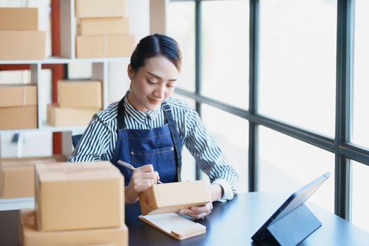 Starting small business entrepreneur of independent Asian female online seller packing products to send to customers and SME delivery concept.