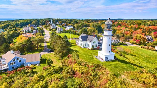 Image of Stunning pair of lighthouses in fall forest with homes surrounding