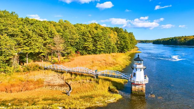 Image of Aerial of small lighthouse Doubling Point on Maine Coast with fall foliage and warm light