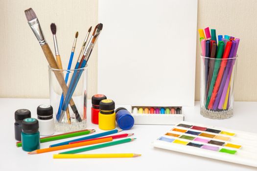 Paintbrushes and colorful drawing supplies on white table: watercolors,pastel crayons, pencils , acrylic paints. Mock up