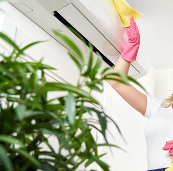 Woman cleaning air conditioner with rag. Cleaning service concept