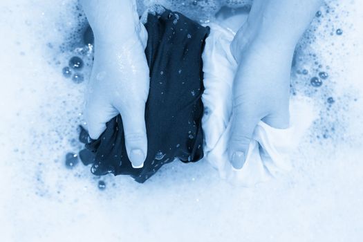 Female hands washing color clothes in basin