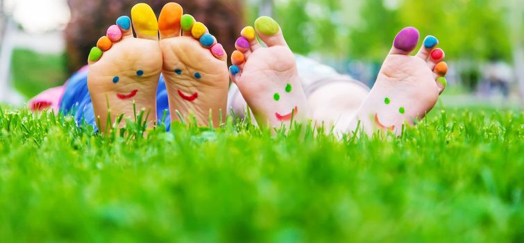 Children's feet with a pattern of paints smile on the green grass. Selective focus.child