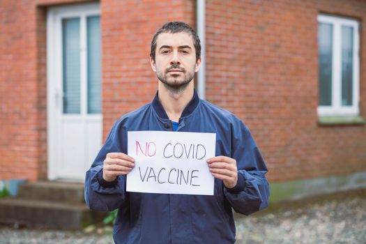 Man holding anti-vaccination poster near his house. 