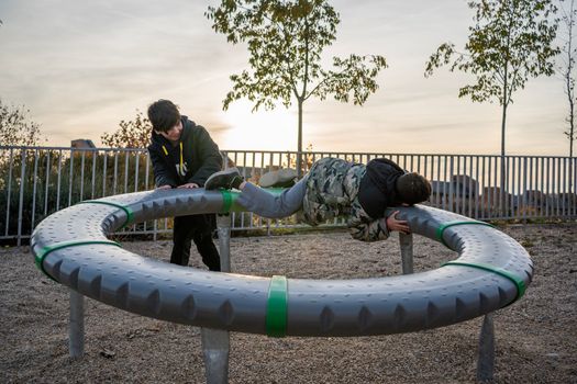 Brothers or friends playing together in the playground at sunset.