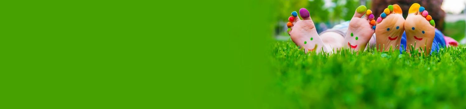 Children's feet with a pattern of paints smile on the green grass. Selective focus.child