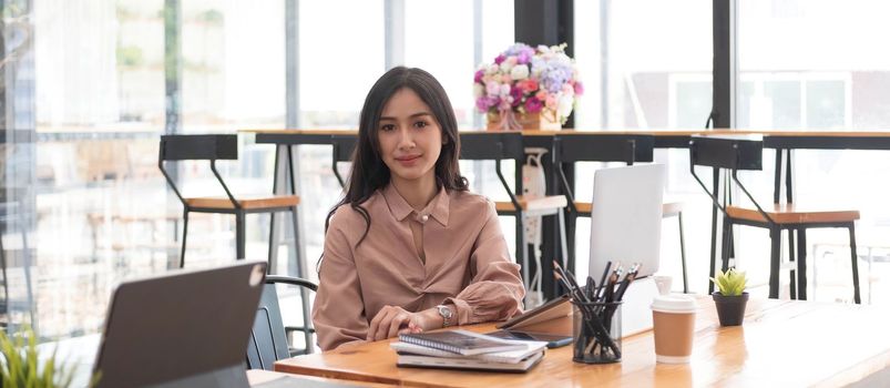 Portrait of a charming Asian business woman working on a laptop in the office...