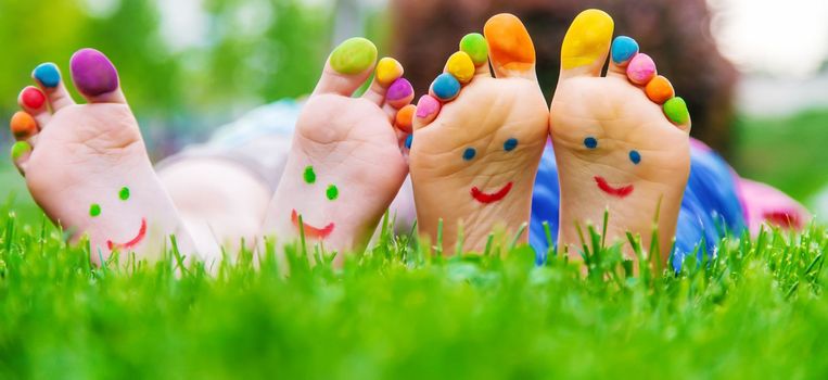 Children's feet with a pattern of paints smile on the green grass. Selective focus.child