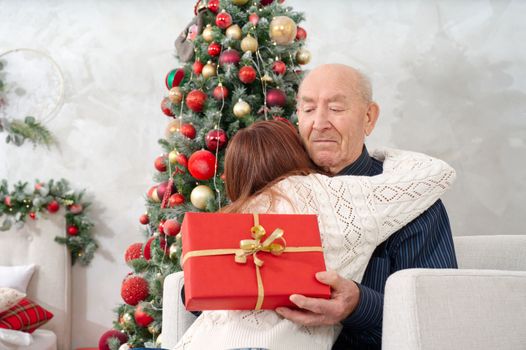great grandfather and great granddaughter. grandfather getting christmas gift from granddaughter. happy elderly man getting a beautiful present. christmas, xmas, holidays, people and family concept