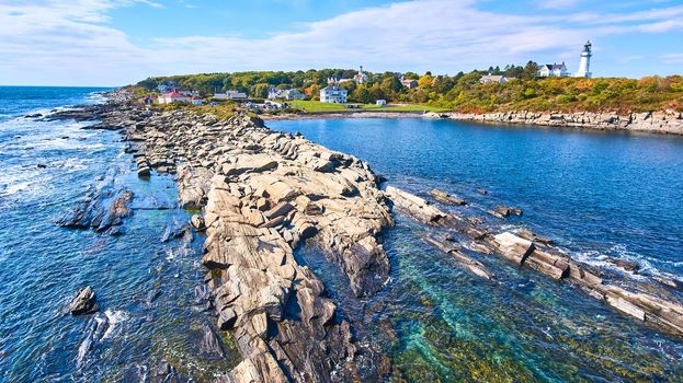 Image of Rocky Maine coastline with shallow waters and lighthouses in background