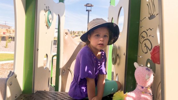 Little girl playing on modern children playground in the suburbs on a hot summer day.