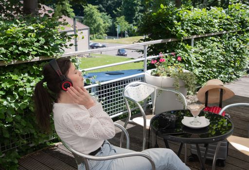 pensive brunette woman in a white blouse, listens to music on headphones at a table in a cafe, High quality photo