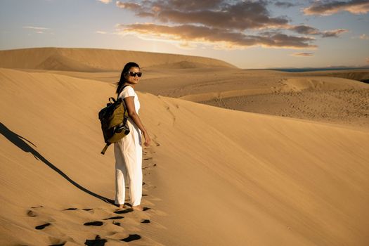 woman walking at the sand dunes of Maspalomas Gran Canaria Spain, girl at the sand dunes desert of Maspalomas Spain Europe