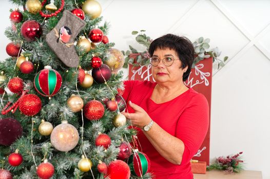 Woman decorating beautiful Christmas tree with ornamets at home, closeup. christmas holidays and people concept. Christmas atmosphere