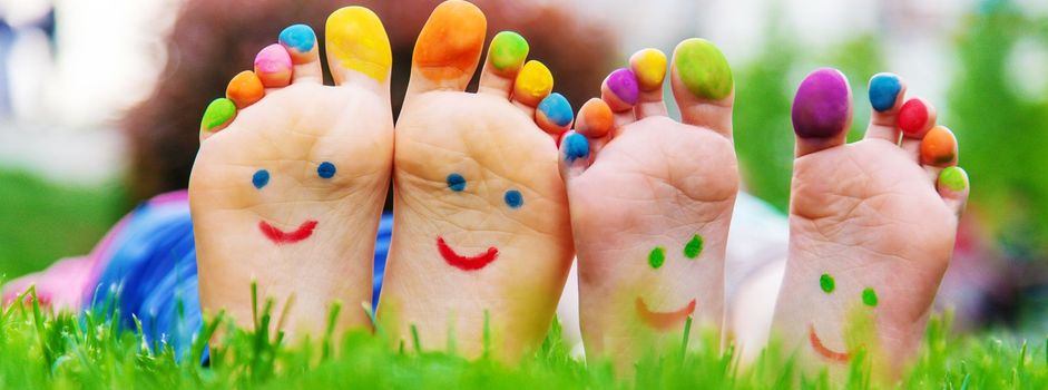 Children's feet with a pattern of paints smile on the green grass. Selective focus.child