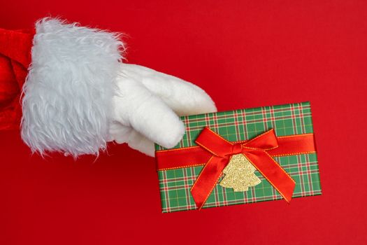 Santa's hands are holding a gift for Christmas. red background with space to copy. Christmas time