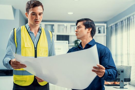 Competent investor investor discuss and brainstorm with engineer on blueprints, construction plans before putting them into action. Professional establishing investment plan for engineering projects.