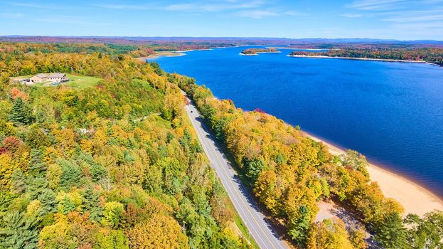 Image of Aerial over fall forest and road along blue lakes in New York