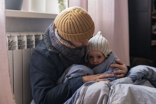 Man wearing warm clothing feeling cold checking central heating battery. Energy crisis in Europe