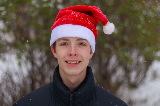 Portrait of a boy 17 years old close-up in a Santa hat.