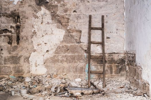 View of a stepladder and wallpaper against a gray rusty dirty concrete wall