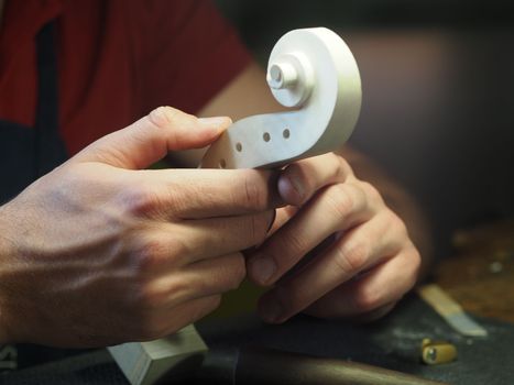 luthier holding a fiddle head studiyng design and carving