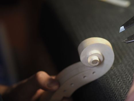 violin maker using a meter to shape and accurate measure fiddle scroll