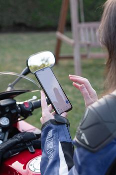 biker girl on a motorcycle enjoys a navigator in a mobile phone, a reflection in the rearview mirror, High quality photo