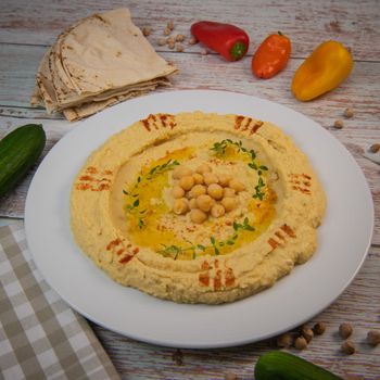 Homemade hummus with tahini plate with olive oil and paprika and pita isolated on brown background. High quality photo