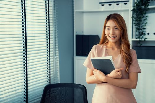 Young competent office lady, intern, secretary holding a log in office room. Concept of various career for office working. Concept of diverse office careers.