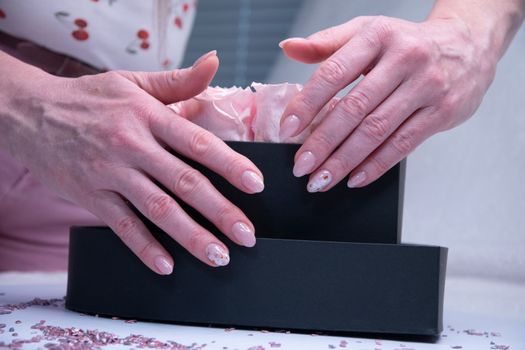 pink wedding manicure for the bride, a girls hand on the black heart shape box. High quality photo