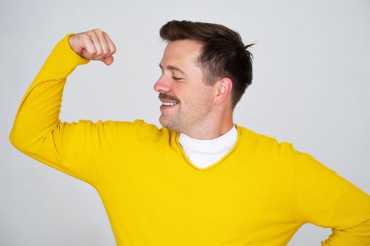 Young caucasian man showing arms muscles smiling proud. Fitness concept. 