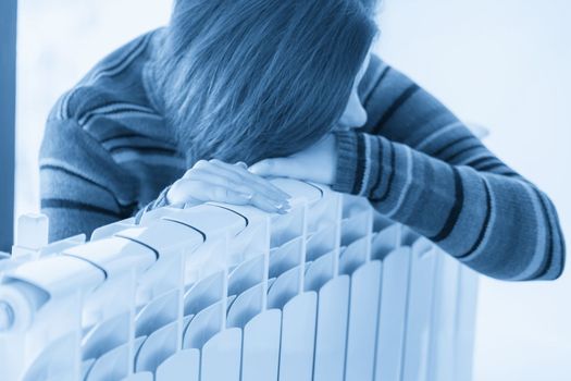 Woman wearing pullover sitting near heater radiator