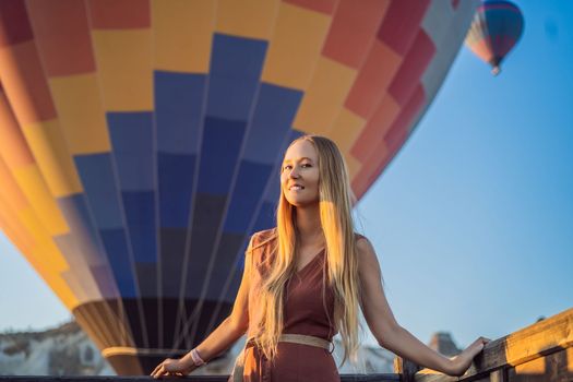 Tourist woman looking at hot air balloons in Cappadocia, Turkey. Happy Travel in Turkey concept. Woman on a mountain top enjoying wonderful view.