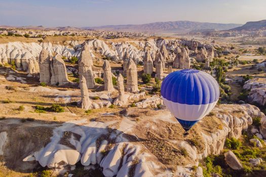 Colorful hot air balloons flying over at fairy chimneys valley in Nevsehir, Goreme, Cappadocia Turkey. Spectacular panoramic drone view of the underground city and ballooning tourism. High quality.