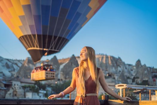 Tourist woman looking at hot air balloons in Cappadocia, Turkey. Happy Travel in Turkey concept. Woman on a mountain top enjoying wonderful view.